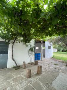 a white building with a tree and two blue trash cans at Casagrande Navarro in Navarro