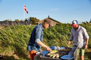 two men standing next to a barbecue grill at Fjand Badeby - Guesthouse, Cottages and Colony in Ulfborg