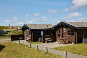 a cabin with a table and chairs in front of it at Fjand Badeby - Guesthouse, Cottages and Colony in Ulfborg