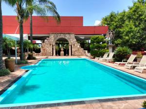 a pool at a hotel with chairs and a building at Villa San Jose Hotel & Suites in Morelia