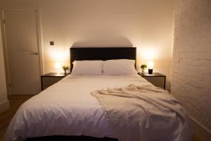 a bedroom with a large white bed with two lamps at Stylish Cosy 4-Bed Home, Sleeps Up To 10 With Large Sofa Bed, Near Manchester Royal Infirmary & Universities, Free Parking & Ultra-Fast WiFi in Manchester +23 photos