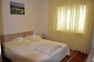ein Schlafzimmer mit einem Bett mit weißen Laken und einem Fenster in der Unterkunft Apartments Zdravko in Orebić