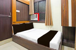a small bed in a room with a window at Hotel O Atithi Restro And Cafe in Dhanbād