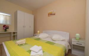 Schlafzimmer mit einem Bett mit gelber Bettwäsche und weißen Kissen in der Unterkunft Apartments Zdravko in Orebić