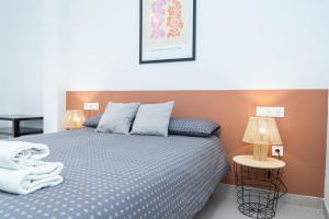 a bedroom with a bed with blue sheets and two lamps at Apartamento Molino y GARAJE in Ronda