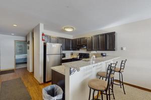 eine Küche mit Theke, Kühlschrank und Stühlen in der Unterkunft Lakeview Peaks in Dillon