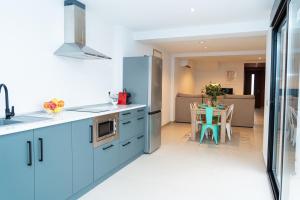 a kitchen with blue cabinets and a table with chairs at Apartamento Molino y GARAJE in Ronda +13 photos