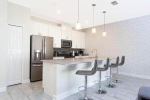 a kitchen with white cabinets and a island with bar stools at 4BD/3BA Champions Gate Home With Private Pool in Davenport