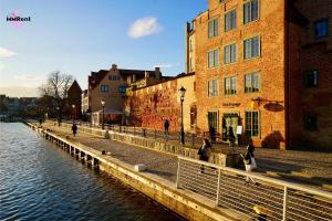 a group of people walking on a sidewalk next to a river at MMRent Mystic Room in Gdańsk