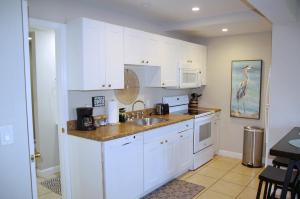 a kitchen with white cabinets and a sink at Naples Park Oasis - Cozy Two Bedroom Apartment in Naples