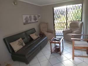 Una sala de estar con un sofá negro y una mesa. en Club Med 23, en Hibberdene