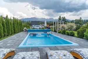 a swimming pool in a patio with two lounge chairs at Domek Dream Holiday in Poronin
