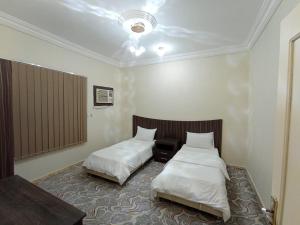 a room with two beds and a table and avertisement at شقق لين in Ḑubā