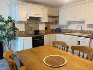 a kitchen with white cabinets and a wooden table with chairs at Turner's hill house in Kingscourt