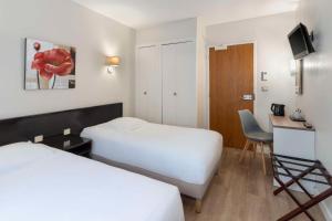 a hotel room with two beds and a desk at Sure Hotel by Best Western Saintes in Saintes