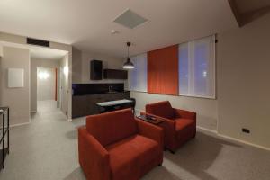 a living room with two orange chairs and a kitchen at Best Western Plus Dimora del Monaco in Matera