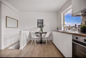 ベルゲンにあるCentral 2 story modern apartmentの白いキッチン(テーブル、白い椅子付)