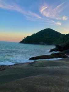 a beach with the ocean and a mountain in the background at Casa na Praia Bertioga in Bertioga