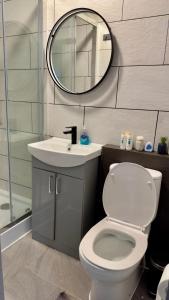 a bathroom with a toilet and a sink and a mirror at Cozy Home in London