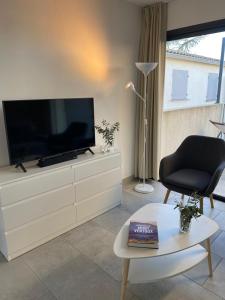 ein Wohnzimmer mit einem Flachbild-TV auf einer Kommode in der Unterkunft Résidence Les Cyclistes, appartement La Musette in Malaucène
