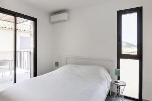 ein weißes Schlafzimmer mit Bett und Balkon in der Unterkunft Résidence Les Cyclistes, appartement La Musette in Malaucène + 16 Fotos