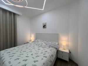 a white bedroom with a bed and two lamps at Luxury Ajman Residence 2 beds in Ajman 