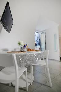 a white dining room table with white chairs and a television at Casa Sant Anna in Naples