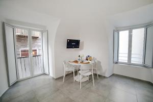 a white dining room with a table and two windows at Casa Sant Anna in Naples