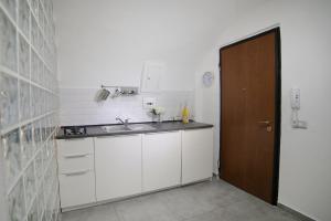a kitchen with white cabinets and a brown door at Casa Sant Anna in Naples