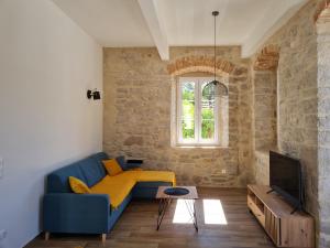 ein Wohnzimmer mit einer blauen Couch und einem Fernseher in der Unterkunft Calico Apartment's in Jelsa