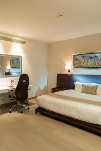 a bedroom with a bed and a desk and a chair at Metria Hotel in León