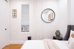 ein Schlafzimmer mit einem Bett und einem Spiegel an der Wand in der Unterkunft 1288-3RS New Renovated 2 Bedrooms in UES in New York