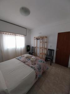 a bedroom with a large bed and a chair at Departamento Marusa in Gualeguaychú