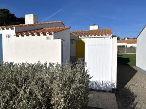 a white fence with a yellow door in a yard at Maison rénovée proche mer avec piscine chauffée, tennis, WiFi, parking privé - Bretignolles-sur-Mer - FR-1-224A-72 in Brétignolles-sur-Mer