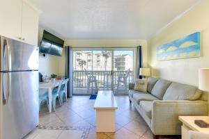 a living room with a couch and a kitchen with a refrigerator at Walk to Galveston Beach Resort Condo with Perks! in Galveston