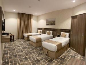 ein Hotelzimmer mit zwei Betten und einem Tisch in der Unterkunft ATYAF ALKHIR HOTEl in Mekka