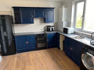 a kitchen with blue cabinets and a black refrigerator at Comfy Room with Dedicated Bathroom 2 in Doncaster