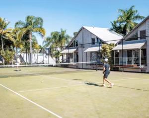 two people playing tennis on a tennis court at Coastal Modern 3 Bedroom Townhouse in Noosaville