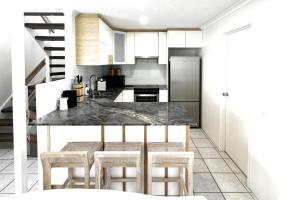 a kitchen with a counter and some chairs in it at Coastal Modern 3 Bedroom Townhouse in Noosaville