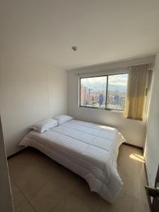 メデジンにあるApartment in Poblado 17th Floor W Poolの大きなベッドと大きな窓のある寝室