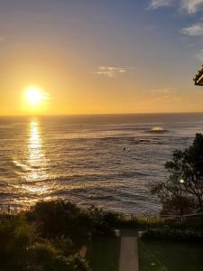a sunset over the ocean with the sun setting at Sunny Apt on The Esplanade - Aircon in Cronulla