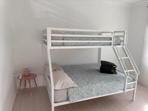 a white bunk bed with a backpack sitting on the floor at Sunny Apt on The Esplanade - Aircon in Cronulla