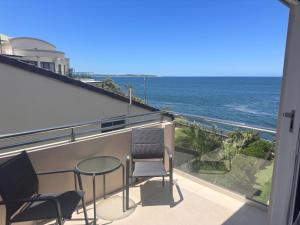 a balcony with two chairs and a table and the ocean at Sunny Apt on The Esplanade - Aircon in Cronulla