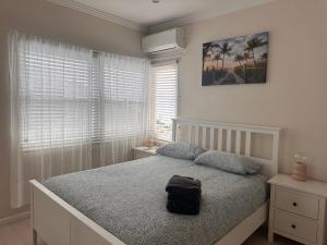 a bedroom with a bed with a black bag on it at Sunny Apt on The Esplanade - Aircon in Cronulla