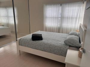 a bedroom with a bed with a black bag on it at Sunny Apt on The Esplanade - Aircon in Cronulla