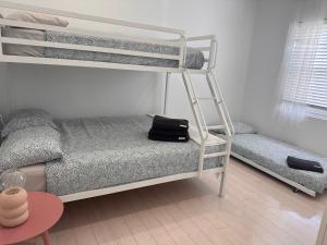 a room with two bunk beds and a table at Sunny Apt on The Esplanade - Aircon in Cronulla