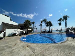 a large swimming pool with palm trees in the background at BNAYAR Tortugas 38, con acceso al Club de Playa in Cruz de Huanacaxtle