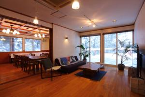 un soggiorno con un divano, un tavolo e delle sedie di Hakuba Third Place Lodge a Hakuba Altre 37 foto
