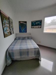 a bedroom with a bed with a plaid blanket at Casa com piscina 2 Guarujá enseada in Guarujá