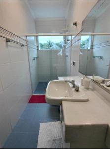 a white bathroom with a sink and a mirror at Casa com piscina 2 Guarujá enseada in Guarujá +1 photo